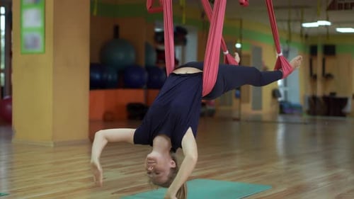 A Young Woman Practices Aerial Yoga Using Special Hammocs