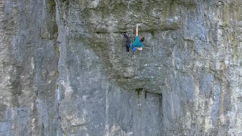 Aerial view of a man rock climbing up a mountain