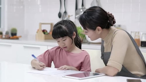 Girl Doing Homework with Mom's Encouragement in Kitchen