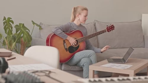 Young Adult Woman Plays Guitar at Home