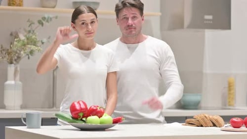 Man and Woman Give Thumbs Down in Kitchen