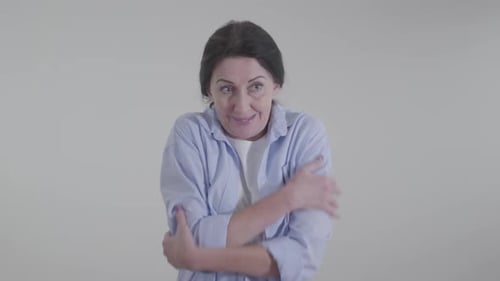 Femme caucasienne gelée se frottant les épaules sur fond blanc. Jeune femme adulte montrant un temps froid