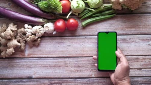 Fresh Vegetables and Holding Mart Phone with Green Screen on Table
