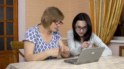 Daughter Teaches Mother How To Use a Laptop. A Young Woman Shows Her Old Mother Where To Click on a