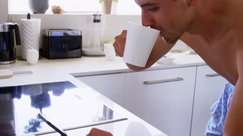 Shirtless Man Drinks Coffee and Uses Tablet