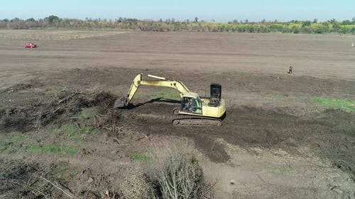 Heavy Machinery Working in the Field Excavator Moving Big Tree Branches