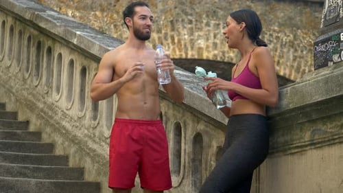 Athletic Couple Hydrating After Workout Talking Outdoors