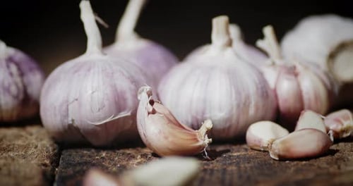 Slices of Unpeeled Garlic Fall on the Wooden Table.