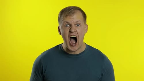Portrait of Young Caucasian Man Posing in Green T-shirt. Shocked Guy Screams, Shakes Head, Says No