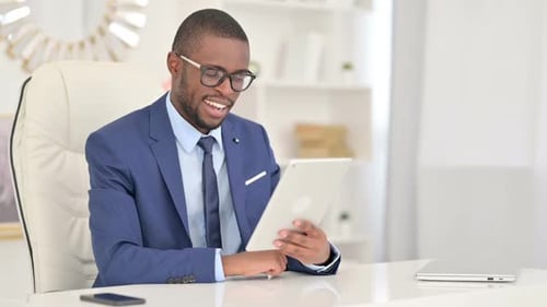 Cheerful African Businessman Doing Video Call on Tablet in Office