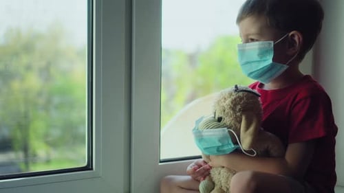 Boy in Mask Holding Stuffed Animal by Window