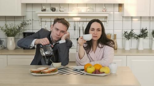 Tired Couple Having Coffee in the Kitchen