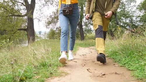 Young Couple Tourists with a Backpacks Walk Through a Forest Road.