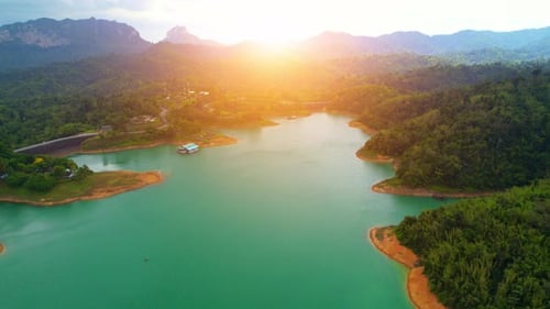 A drone flying over a dam in a beautiful tropical forest.