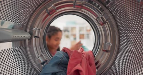 Inside the Washing Machine a Little Girl Puts Colorful Clothes Into the Drum She Helps Her Mother