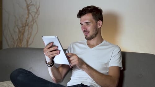 Man Relaxing on Couch Using Tablet Device