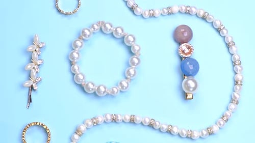 Flat Composition of Jewelry with Pearls Necklace Beads Rings Hairpins and Gems on a Blue Background