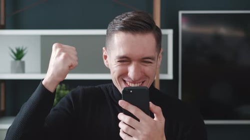 Excited man cheers looking at his smart phone