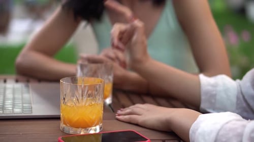 Konzept für Kommunikation und Freundschaft: Junge Frauen sprechen im Café im Freien und teilen gute Nachrichten