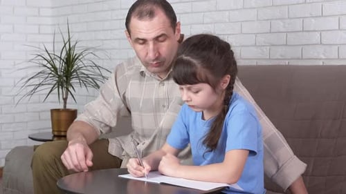 Father Assists Daughter with Homework in Living Room