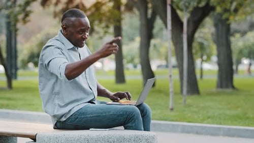 Adult Mature African American Man Professional Using Laptop Computer Sitting Outdoors in City Park