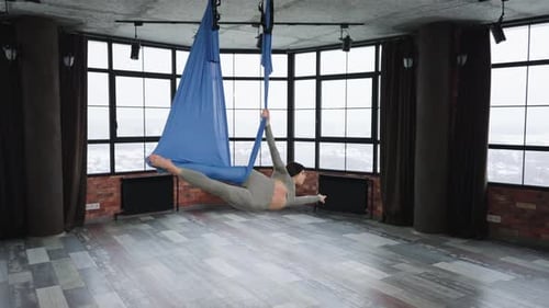 Woman Practicing Aerial Yoga in Modern Studio