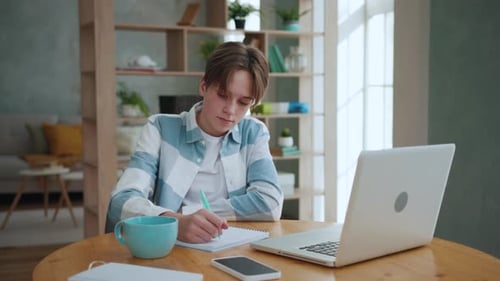 Teen Studying at Desk, Writing in Notebook
