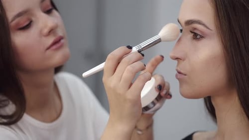 Brunette Applying Makeup to Face with Brush
