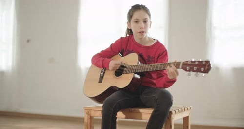 Girl Plays Guitar and Sings Song Indoors