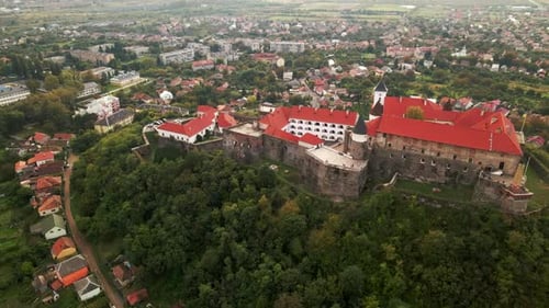 Luftaufnahme der mittelalterlichen Burg auf einem Berg in einer kleinen europäischen Stadt an bewölktem Herbsttag