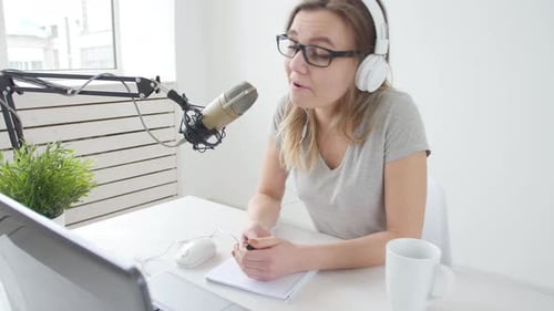 Concept of Streaming and Broadcasting. Young Cheerful Girl in the Studio Speaks Into a Microphone