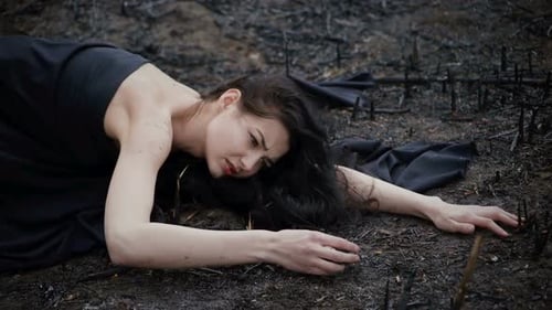Distressed Woman Lying on Burned Wasteland