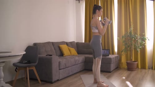 Young Woman Working Out with Dumbbells at Home