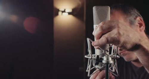 Sound engineer working in a recording studio with a sound console and microphones