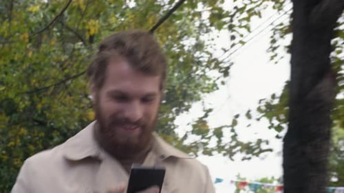 Man Smiles While Using Phone Outside