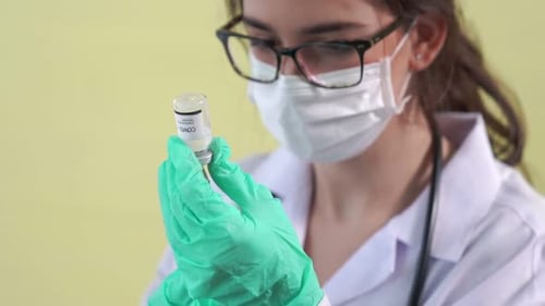 Medical Professional Preparing Vaccine With Syringe