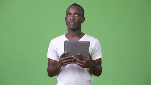 Young Adult Holding Tablet in Front of Green Screen