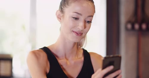 Young Woman Using Smartphone In Gym