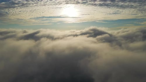 Aerial View of Vibrant Yellow Sunrise Over White Dense Clouds with Blue Sky Overhead