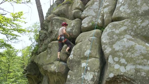 Young Man Climbing Steep Wall of Rocky Mountain