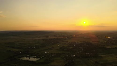 Aerial Landscape View of Green Cultivated Agricultural Fields with Growing Crops and Distant Village