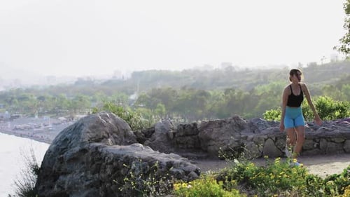 A Sporty Woman Warms Up Before Training on a Rocky Elevation