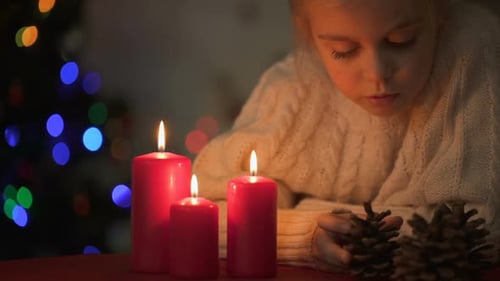 Child Contemplates Candles and Pinecones near Christmas Tree