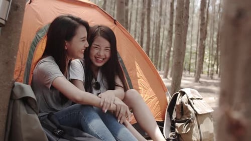 Women couple camping together in forest, teenager enjoy moment talking in front of their tent