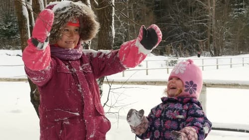 Schöne Kinder werfen eine Handvoll Schnee in die Luft.