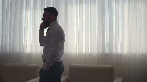 Serious Businessman Talking on Mobile Phone in Office