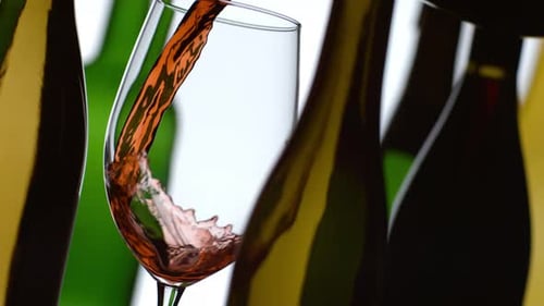 Vin rouge coulant au Ralenti avec des bouteilles en arrière-plan ; filmé sur Phantom Flex 4K à 1000 images par seconde