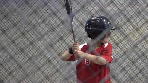 Young Baseball Player Practicing Batting in Cage