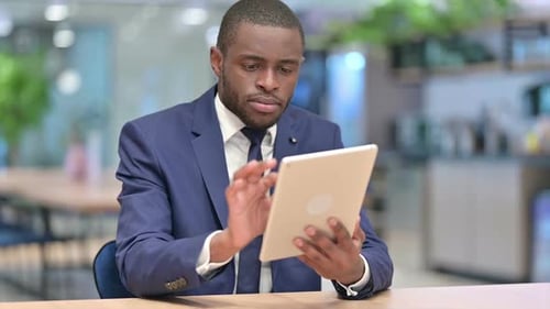 Serious African Businessman Using Tablet in Office
