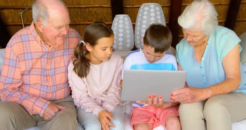 Front view of multi-generation Caucasian family using laptop in a comfortable home 4k